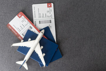 Toy airplane and passport with tickets on gray background, top view