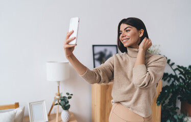 Smiling young ethnic female millennial taking selfie at home