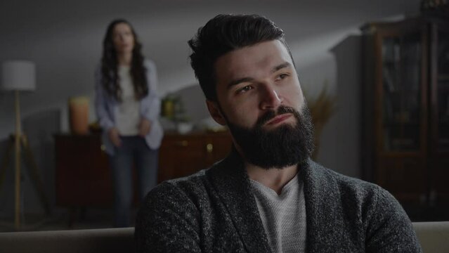 Close-up anxious husband feeling stress while his aggressive wife blaming him during family quarrel.