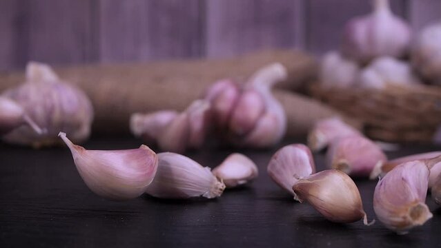 Fresh garlic clove falling on black background. The raw garlic is one of the most popular ingredients of the basic recipes with nutritional properties, infamous aroma and health benefits. Slow motion