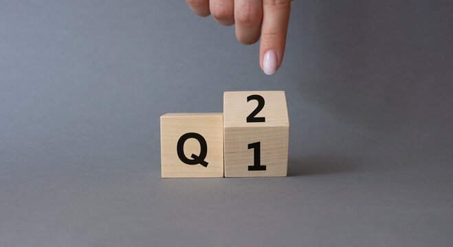 From 1st Quarter to 2nd symbol. Businessman hand points at turned wooden cubes with words 1st Quarter and 2nd Quarter. Beautiful grey background. Business and Quarter concept. Copy space