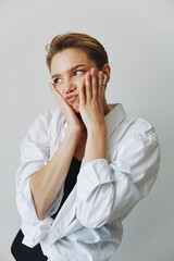 Young woman teenager listening to music with infertile headphones and dancing home, grinning with teeth with a short haircut in a white shirt on a white background. Girl natural poses with no filters