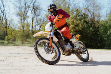 Naklejka na ściany i meble Man riding motorbike on motocross track.Extreme and Adrenaline. Motocross rider in action. Motocross sport. Active lifestyle