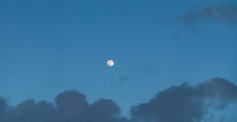 Beautiful full moon on the  blue sky in the clouds.