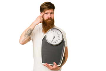 Adult redhead man with long beard holding a scale isolated cut out pointing temple with finger, thinking, focused on a task.