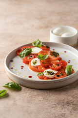Caprese salad in modern linear feed with tomatoes, basil, mozzarella, pesto, balsamic sauce and olive oil. Traditional Italian food on beige background, copy space