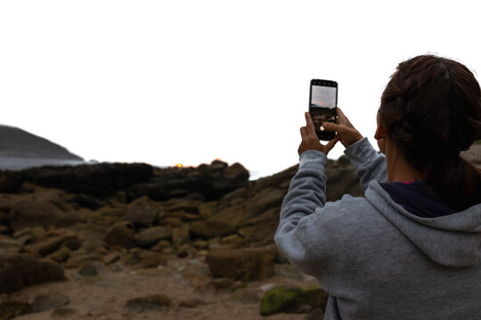 The girl takes pictures of the sunset on her phone, the view from the back.