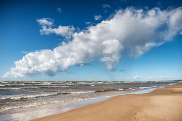 Beautiful seascape, spikelets on the background of a sandy beach sky with clouds and cold sea, Baltic Sea, Latvia