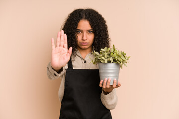 Young african american gardener woman holding a plant isolated standing with outstretched hand...
