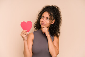 Young african american woman holding a heart for valentines day isolated looking sideways with...