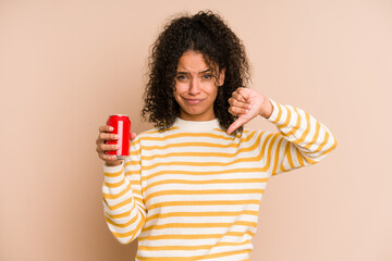 Young african american woman holding a cola refreshment isolated showing a dislike gesture, thumbs...