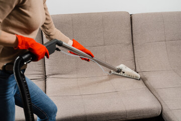 Cleaner girl is cleaning couch with mop extractor dry cleaning machine at clients home. Housewife dry cleaning of couch and removing dust, stains and dirt using mop extractor machine.