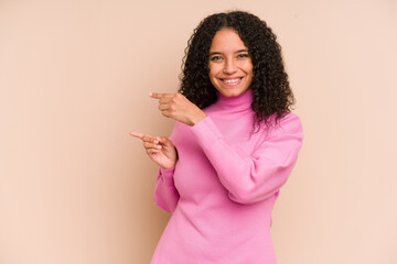 Young african american curly woman isolated excited pointing with forefingers away.