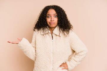 Young african american curly woman isolated showing a copy space on a palm and holding another hand...