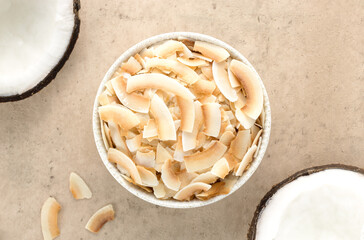Coconut chips or coconut flakes with fresh half coconuts on a beige background. Top view.. Healthy snacks. Coconut dessert. 