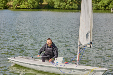 man on laser boat with sail on water