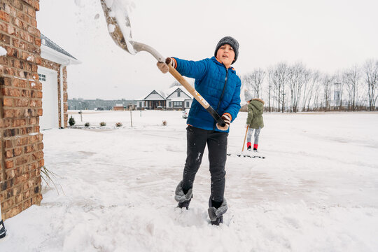 Boy playfully throwing snow from a shovel. 