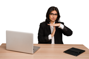 Young indian woman in a table with a laptop and tablet isolated showing a timeout gesture.