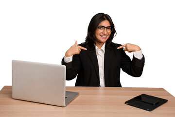 Young indian woman in a table with a laptop and tablet isolated surprised pointing with finger,...