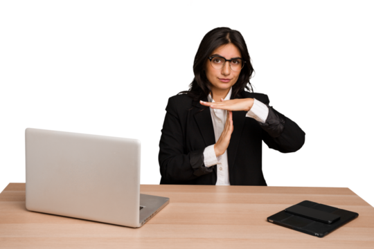 Young indian woman in a table with a laptop and tablet isolated showing a timeout gesture.