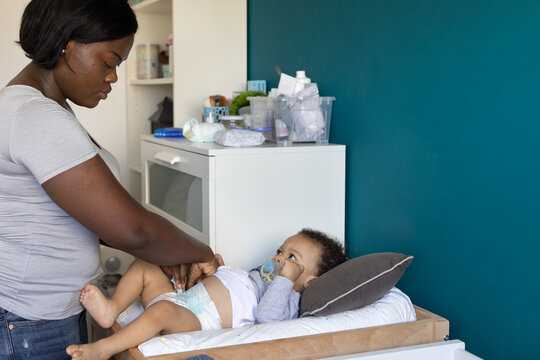 woman mother changing diaper of baby at home