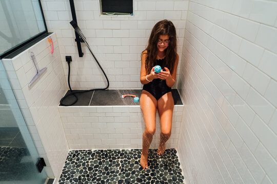 Girl reading the directions on a bottle of shaving cream.