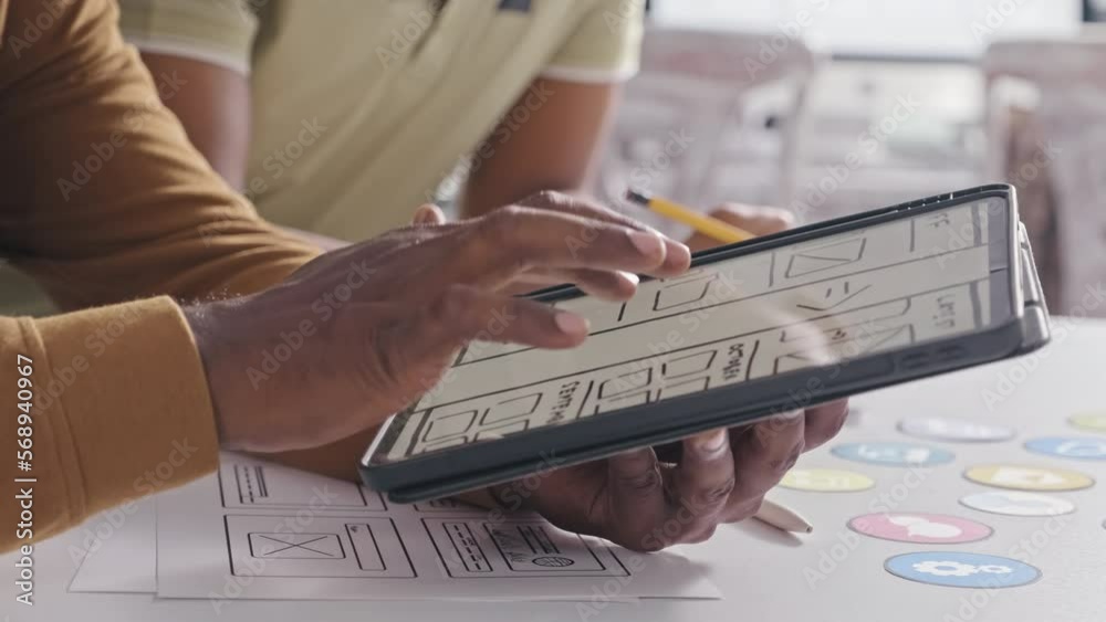 Wall mural close up shot of hands of ux designer showing digital sketch of mobile app interface on tablet while