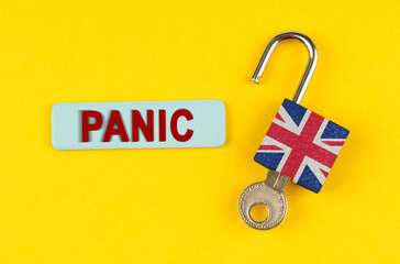 On the yellow surface is an open lock with a key and a sticker with the inscription - Panic