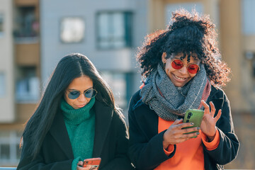 two girls friends in the street with mobile phone
