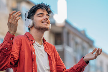 young man with headphones relaxed enjoying listening to music outdoors