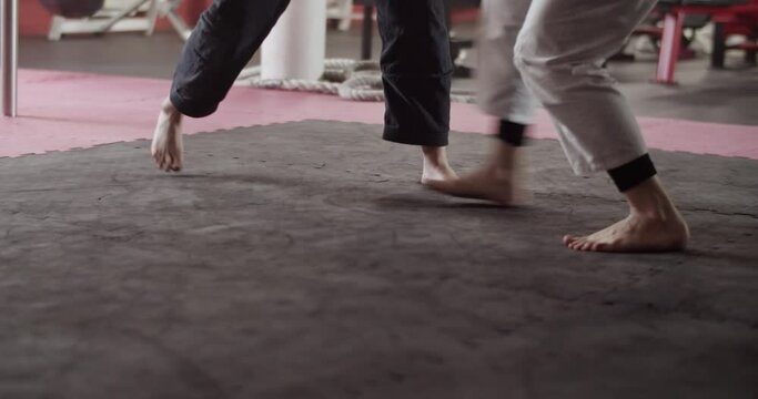 Crop barefoot women sparring in gym