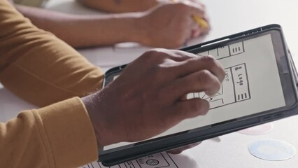Close up shot of hands of UX designer discussing mockup of mobile app interface on digital tablet with colleagues while cooperating in office - Powered by Adobe