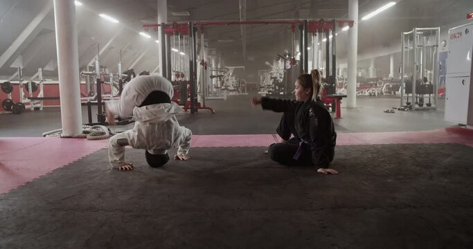 Muslim woman doing headstand drill near trainer