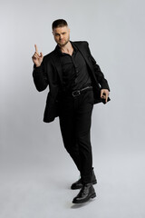  Photo of a European-looking man in a black suit posing in a James Bond style in a studio