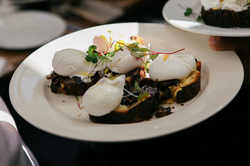 plate of poached eggs on toast on white plate in sunny restaurant