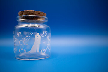 glass bottle for valentine’s day with blue background and white hearts. Design of two people in love kissing. Wedding favor