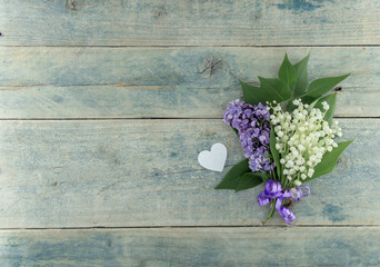 Bouquet of flowers lily of the valley and Lilac with heart on turquoise rustic table. Greeting card for Valentine's Day, Woman's Day and Mother's Day holidays. Spring love  background. Top view