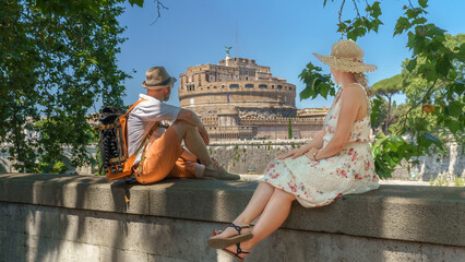 Ein Paar sitz auf einer Mauer am Tiber mit Blick auf die Engelsburg in Rom, Italien, Europa.