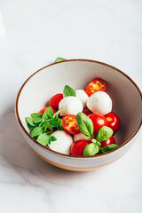 Classic italian salad caprese served in original form with cherry tomatoes, mini mozarella pearls and basil