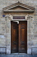 Fototapeta na wymiar Paris ancient stone building entrance with stone walls, triangular fronton and wooden carved door