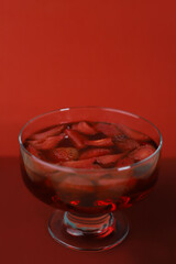 sweet tasty refreshing strawberry jelly berry dessert in a transparent glass with fresh strawberries on a red background. for business cards, labels, splash screens, banners, flyers, advertisements, m