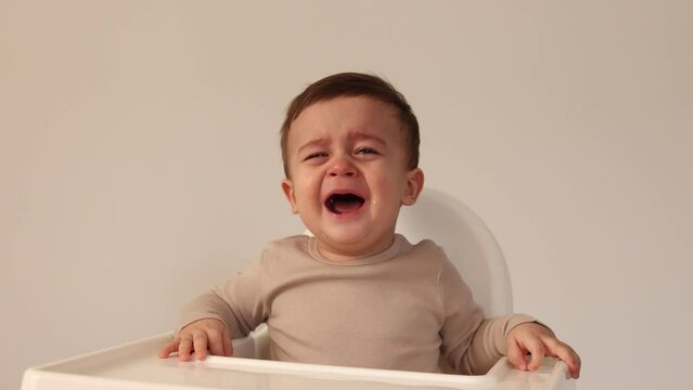 cute baby in a baby chair at home crying. High quality 4k footage
