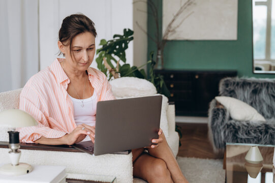 Middle aged female using laptop on settee
