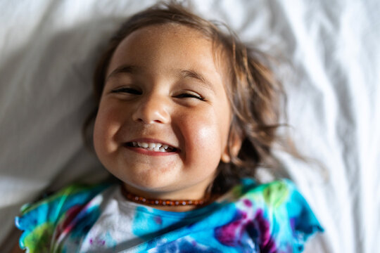 Happy little girl on bed funny portrait