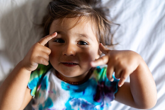 Funny little girl with funny gestures from the bed