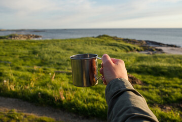 Close-up of male hand holding mug. The adventure begins travel, hiking and camping concept
