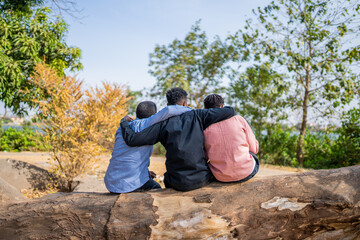 Three queer masculine women share a hug at the park