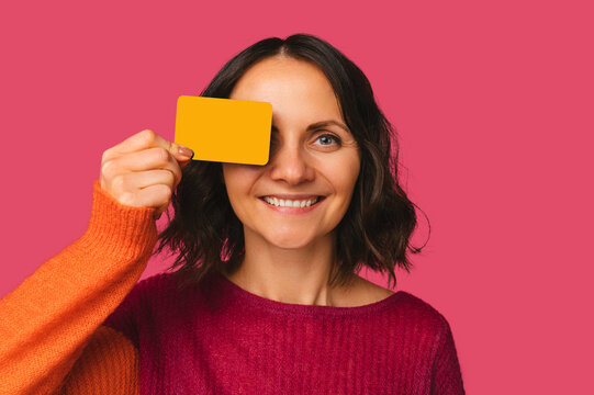 Close Up Shot Of A Wide Smiling Woman Cover One Eye With A Credit Card.