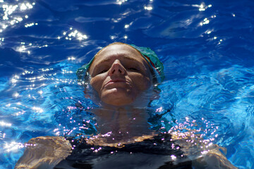 A woman wearing a bandana relaxs in a swimming pool