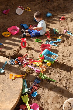baby plays in sandbox with a lot of toys